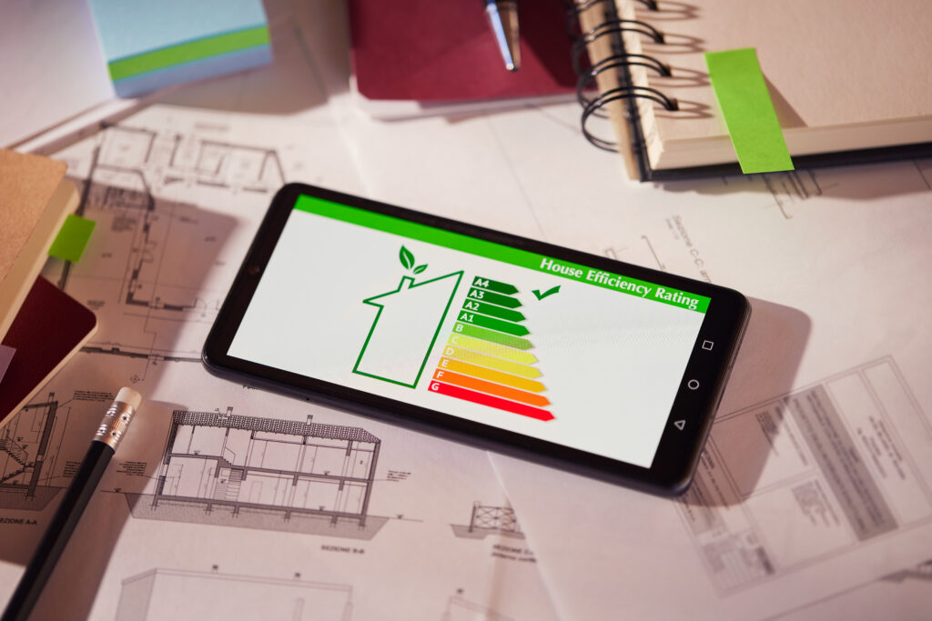 smartphone toont energielabel van een woning bovenop bouwplannen