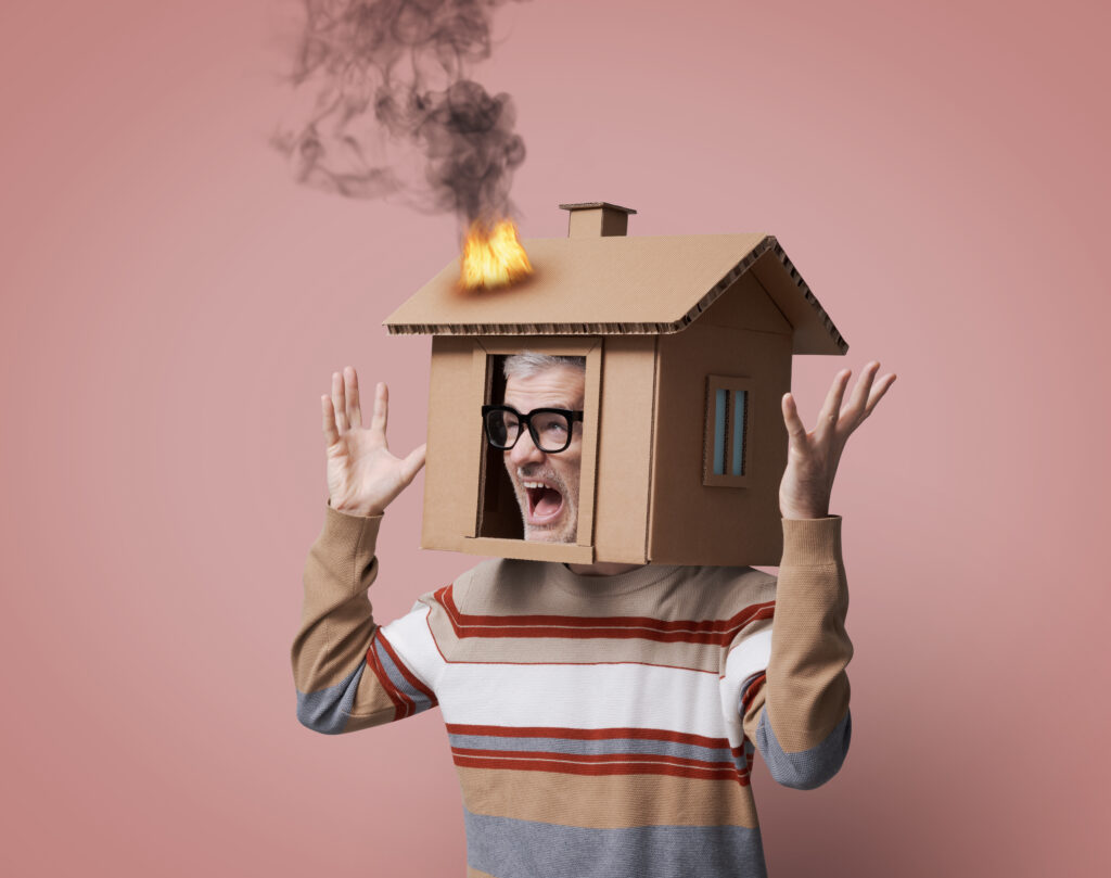 man schreeuwt met een brandend kartonnen huis over zijn hoofd
