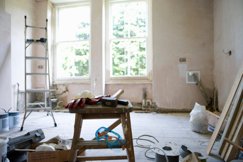 kamer in renovatie met ladder, hamer, werkhandschoenen en verfblikken